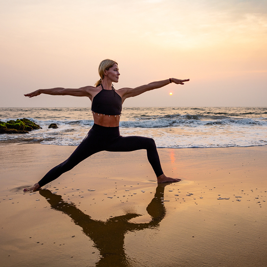 Frau praktiziert Yoga am Strand während des Sonnenuntergangs auf den Seychellen.