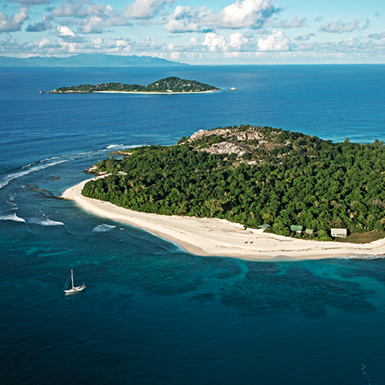 Eine tropische Insel der Seychellen mit weißem Sand und klarem blauen Wasser.
