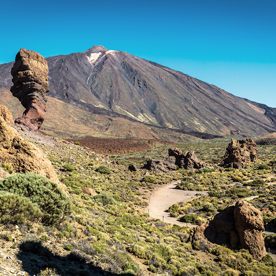 Ein Berg auf den Kanaren mit einer Strasse und einer markanten Felsformation im Vordergrund.