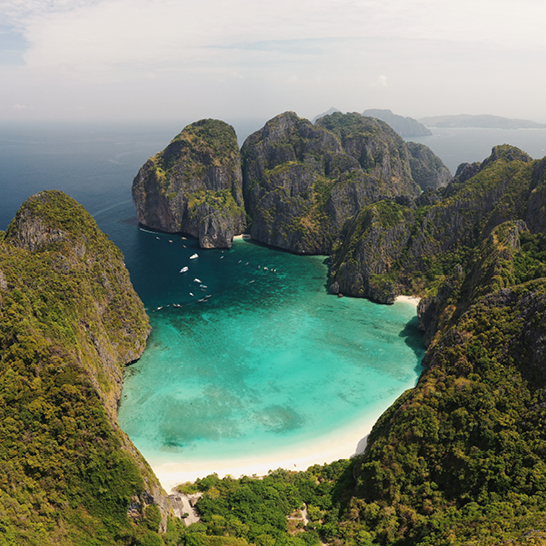 Blick auf einen Strand mit einer beeindruckenden Bergkette im Hintergrund, typisch für die Inseln Thailands.