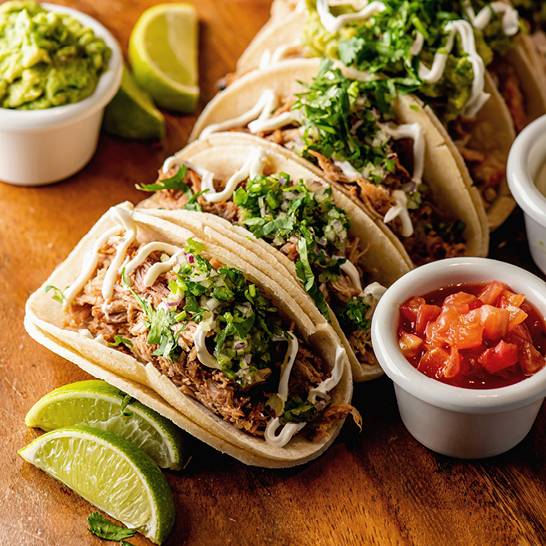 Leckere Tacos mit frischer Guacamole und Limettenscheiben, bereit zum Geniessen.