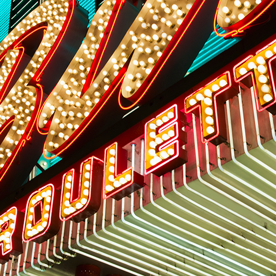 Neon-Schild eines Casinos mit dem Slogan "USA Bigger is better" in leuchtenden Farben.