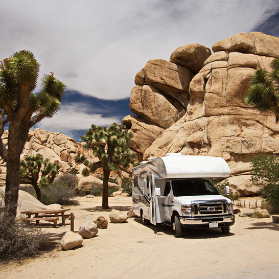 Ein weisser Wohnmobil steht in einer Wüstenlandschaft in den USA.