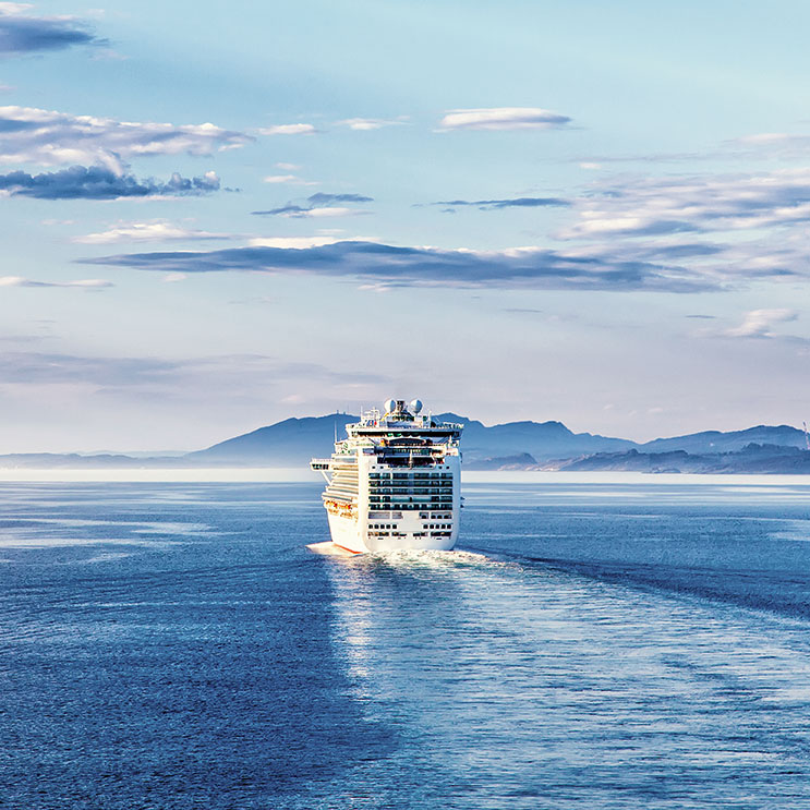 Kreuzfahrtschiff auf dem Meer, das ruhig über das Wasser gleitet, mit klarem Himmel und einem Panoramablick auf den Horizont.