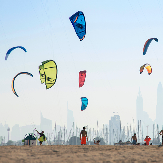 Kitesurf-Drachen fliegen über dem öffentlichen Strand von Jumeirah in Dubai, Vereinigte Arabische Emirate.