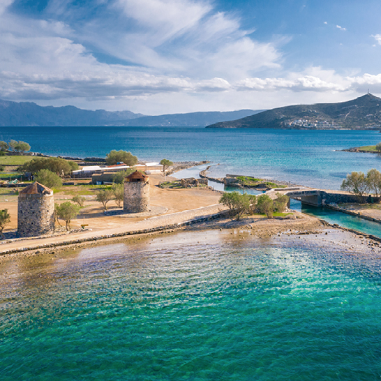 Ein Boot schwimmt im Wasser neben einem Strand in Kreta Elounda.