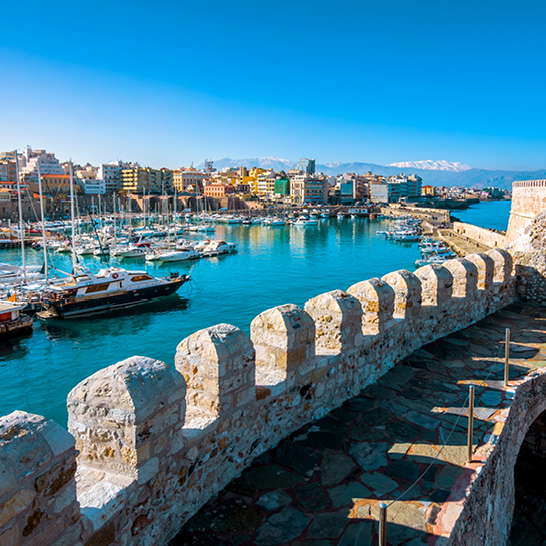 Blick auf den Hafen von Kreta Heraklion mit Booten und einer Brücke im Hintergrund.