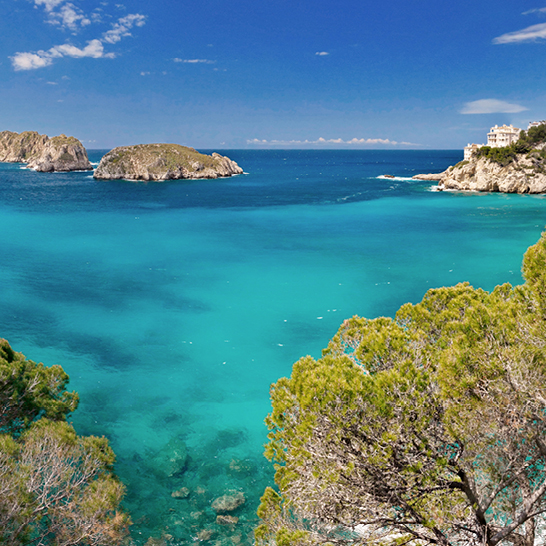Wunderschönes blaues Wasser des Ozeans, umgeben von Bäumen in Santa Ponsa, Mallorca.