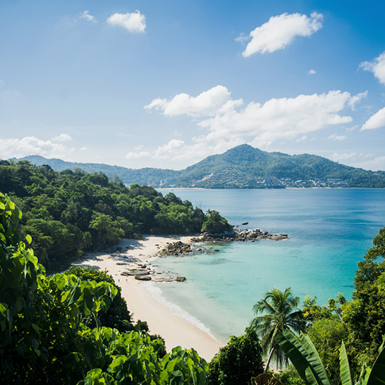 Kamala Beach in Phuket, Thailand. Die Buchtlandschaft am Kamala Beach in Phuket zeigt weißen Sand, blaues Meer und blauen Himmel.