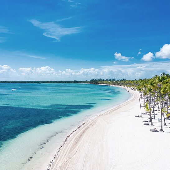 Luftaufnahme des wunderschönen Strandes von Bavaro mit weissem Sand und Palmen. Türkisfarbenes Wasser und blauer Himmel. Sommerferien im All-inclusive-Resort und Hotel von Punta Cana.