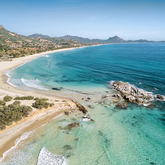 Luftaufnahme von Costa Rei in Sardinien, die den Strand und die umliegenden Berge zeigt.