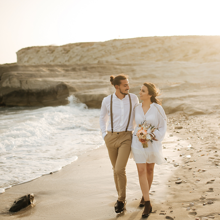 Erneuerung der Ehegelübde am Strand, mit einem atemberaubenden Sonnenuntergang im Hintergrund und einer intimen, romantischen Atmosphäre.