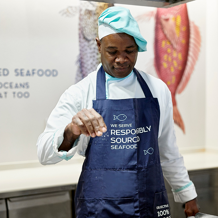 Der Koch würzt den Fisch aus verantwortungsvollen Quellen